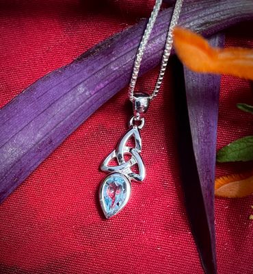 Sterling silver Trinity Knot pendant with blue topaz birthstone, Celtic jewelry symbolizing faith and unity.