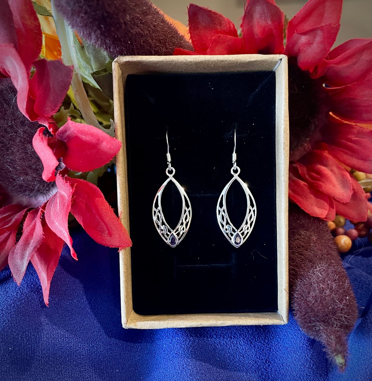 Oval Celtic Knot Earrings with Scottish Accents Sterling silver oval earrings featuring intricate Celtic knots and a radiant amethyst-colored stone, inspired by Scotland.