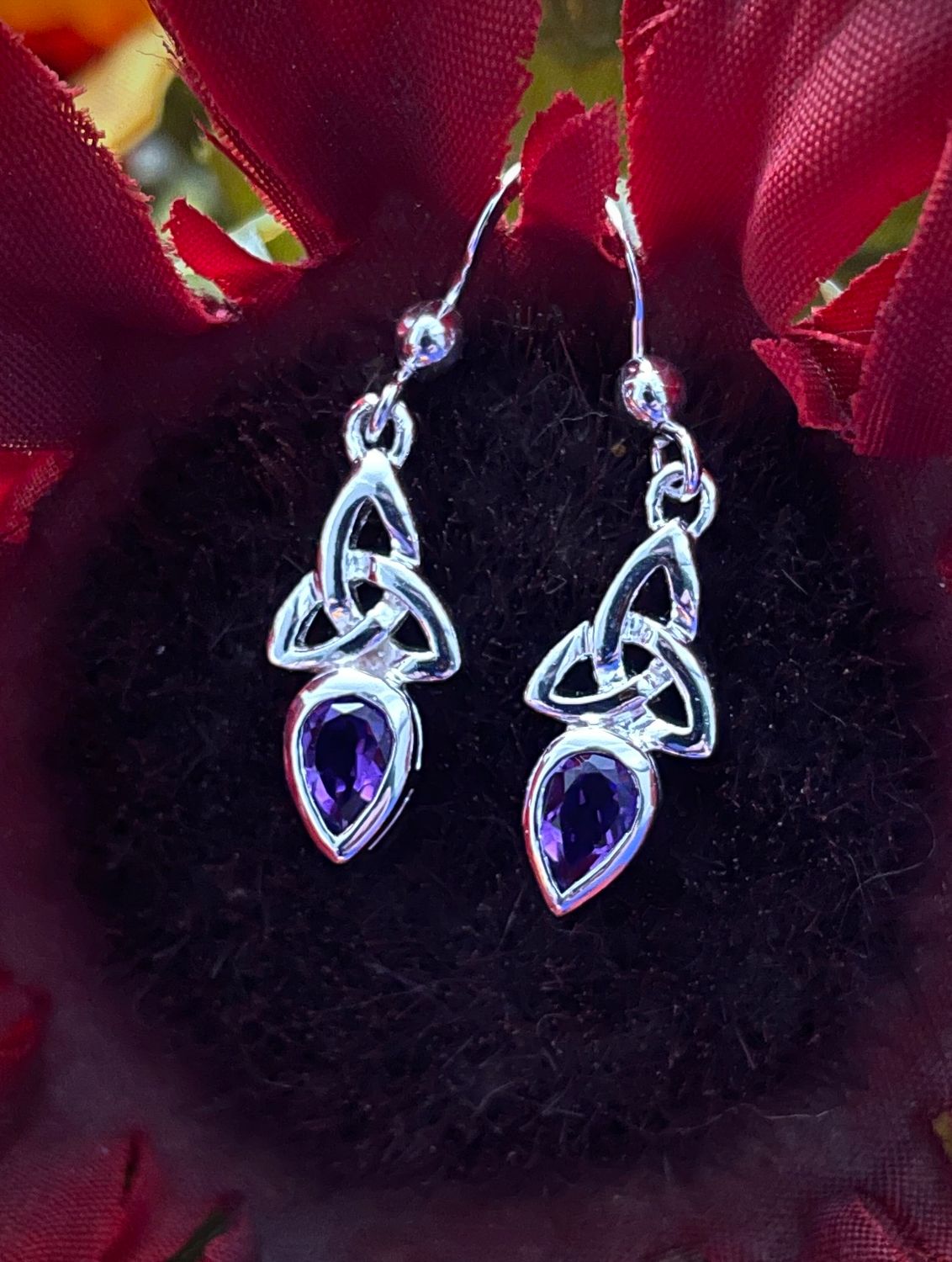 Trinity Knot and Amethyst Earrings Sterling silver Trinity Knot earrings featuring an amethyst-colored gemstone, celebrating Celtic tradition.