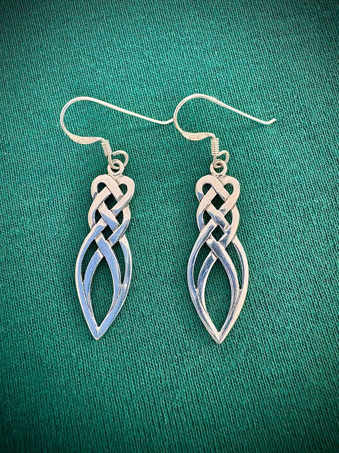 Endless Celtic Knot Drop Earrings Sterling Silver Celtic Knot Drop Earrings on Green Fabric.