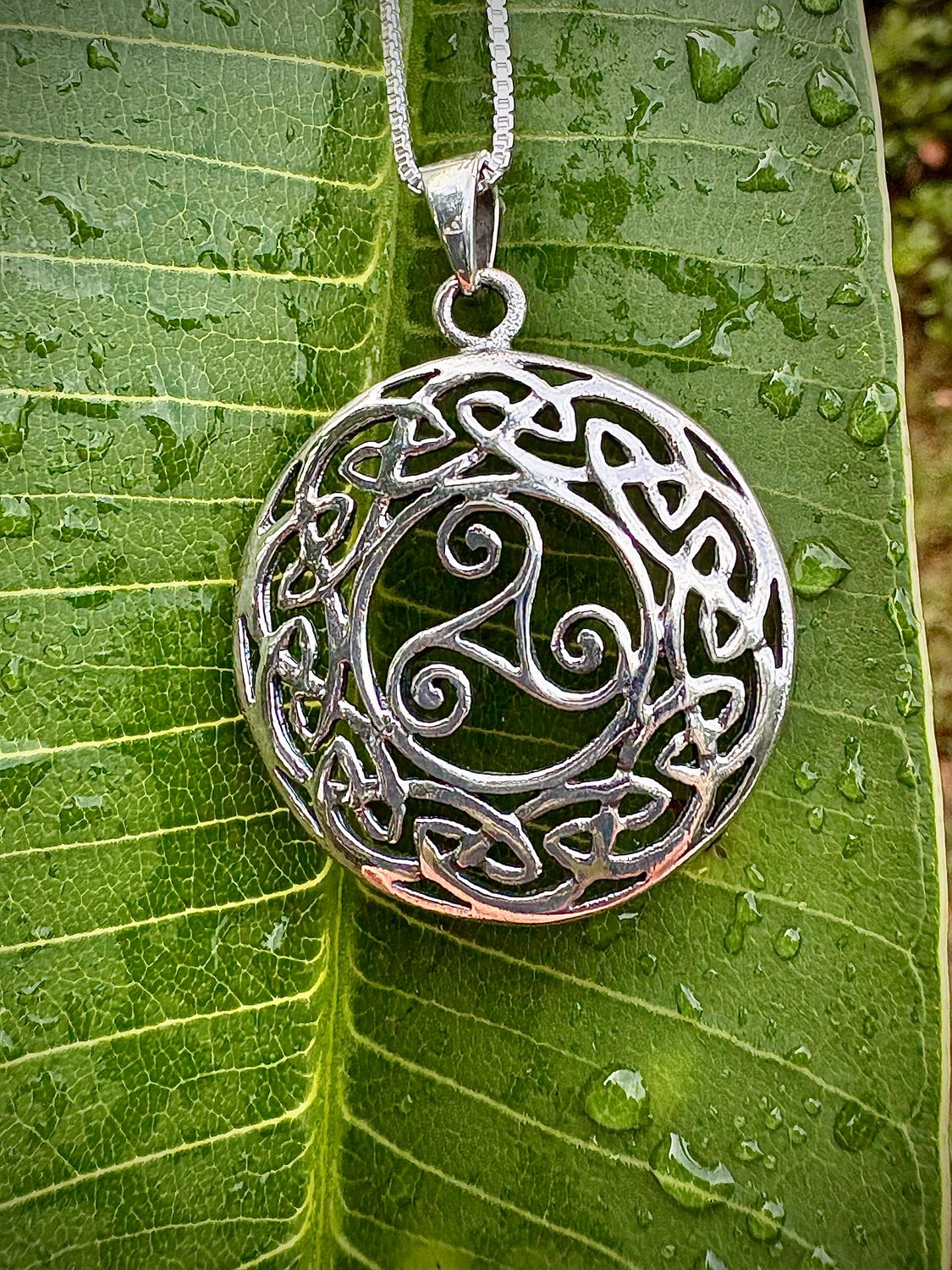 Triskele in Celtic Knotwork Pendant Sterling Silver Celtic Knotwork Pendant with Triskele symbol, representing everlasting motherly love, shown on leaf.